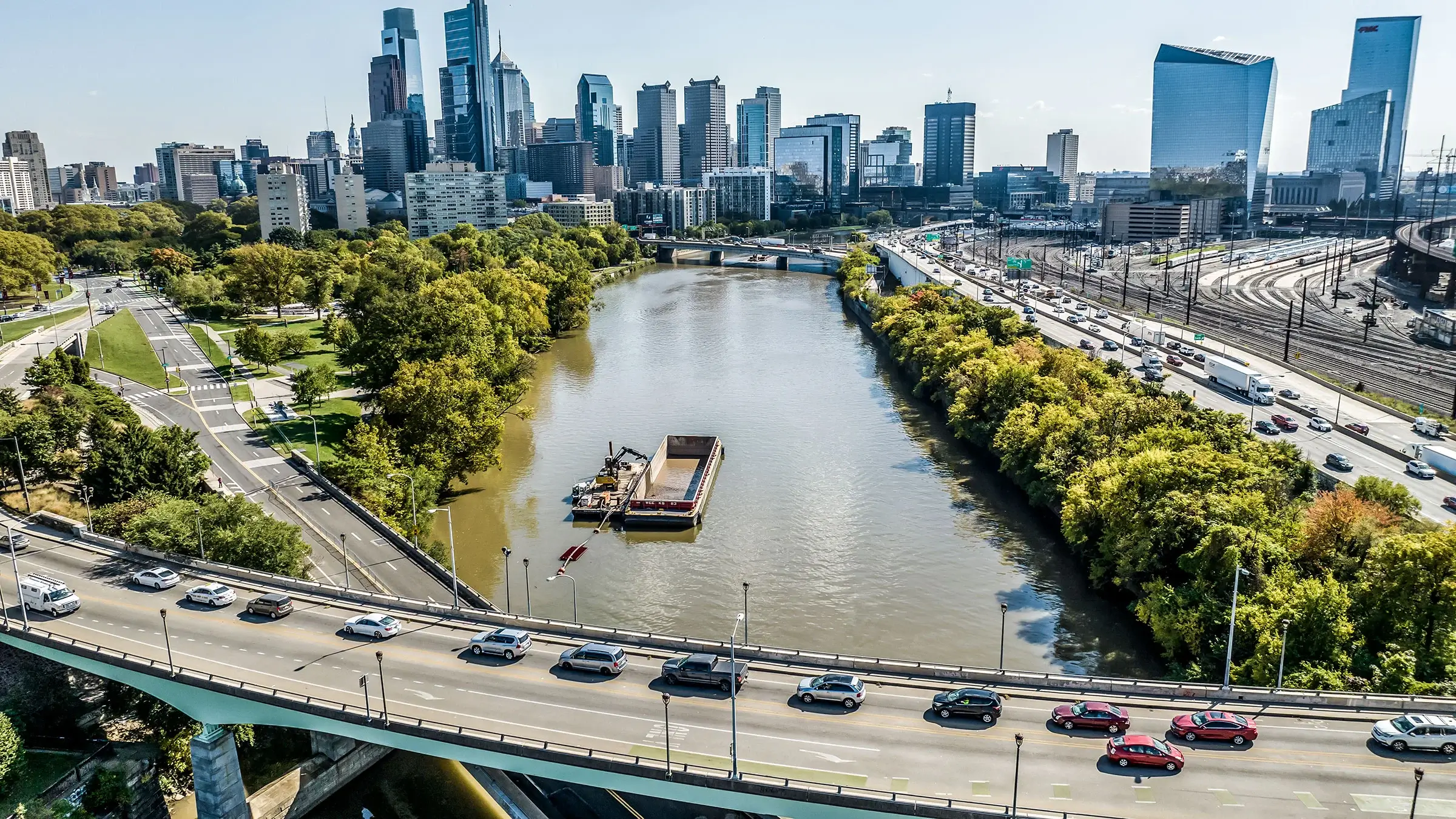 Cars on a busy bridge drive over the Schuylkill River.